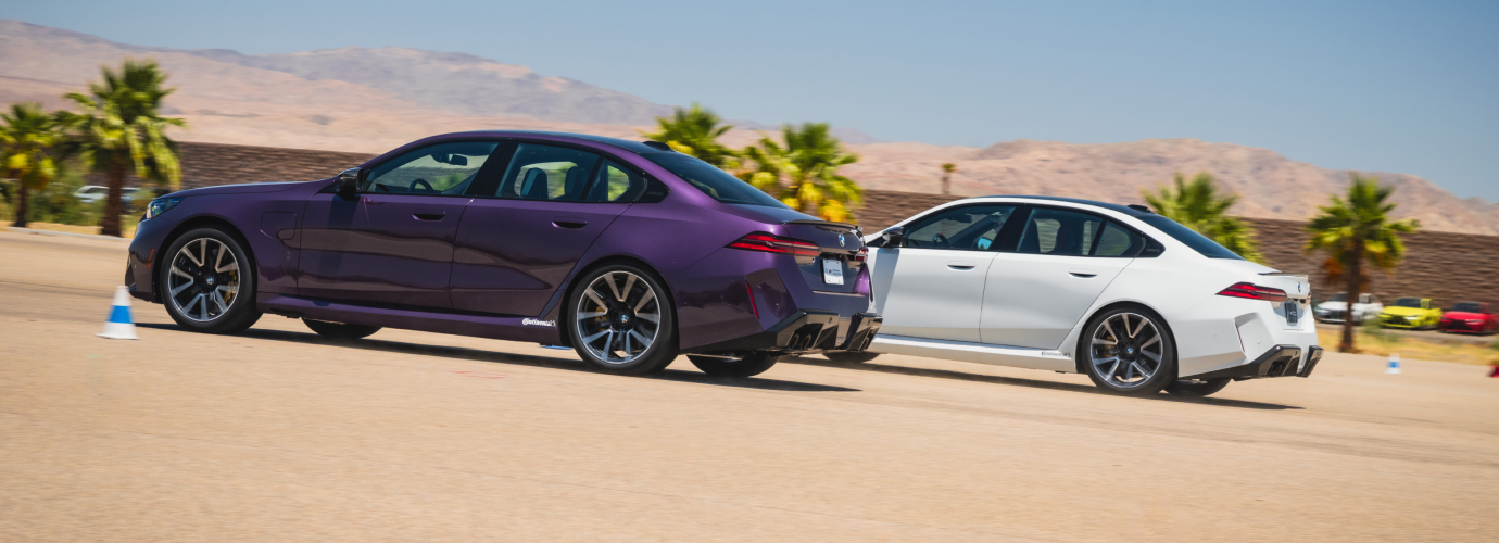 Purple BMW M5 alongside a white M5 on the desert apron