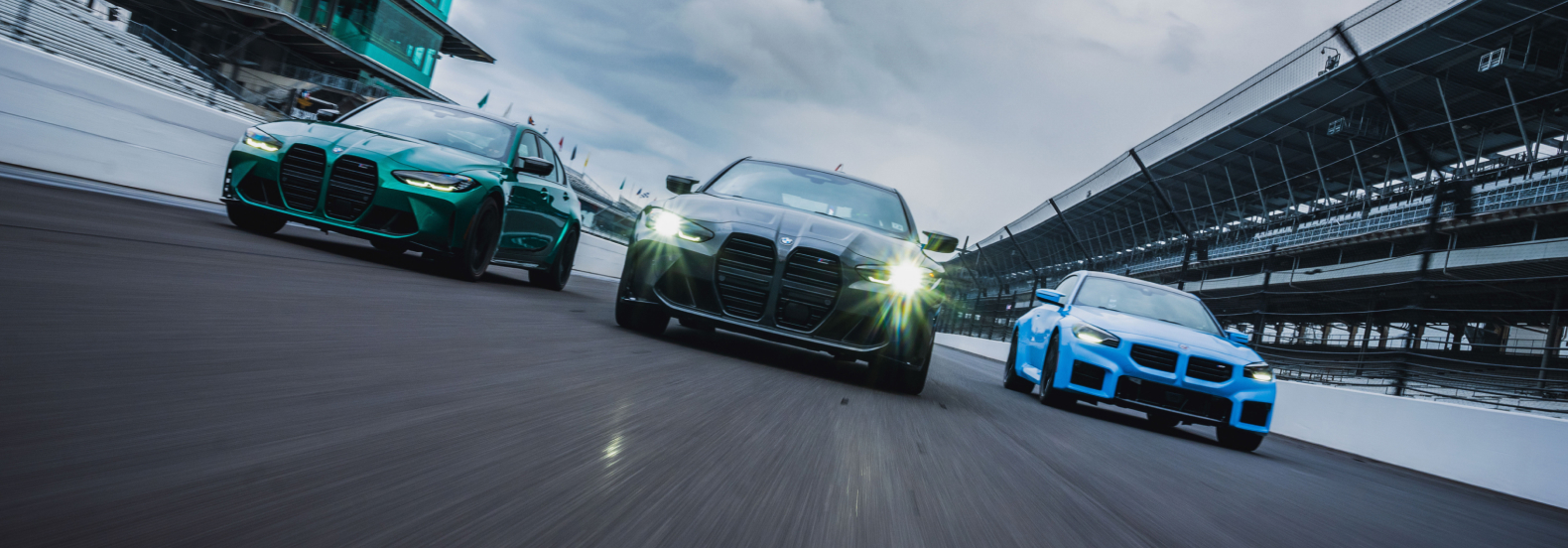 Three BMW cars on track at dusk.