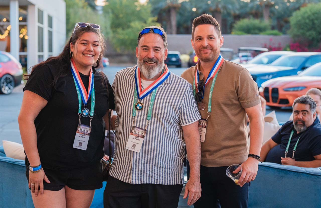 Three class participants pose for a photo during a group event at a BMW Performance Driving School.