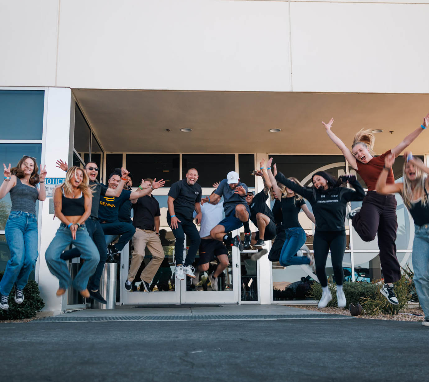 Twelve class participants jump in the air to celebrate the kickoff of their group event at a BMW Performance Driving School.